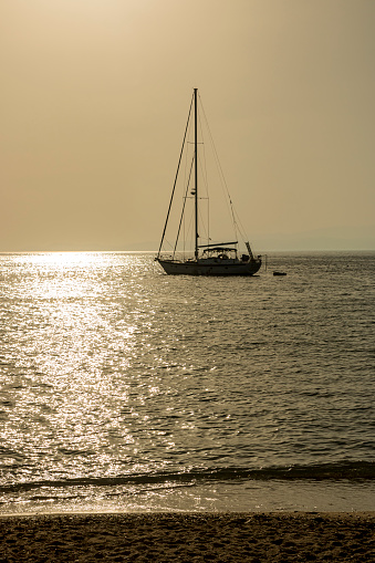 Small boats and yachts at sunset docked on the marina park with oceanfront view in Greece.