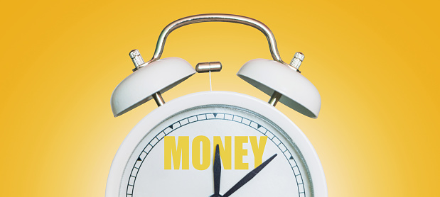 Time for money. White vintage clock pointing to Money on a yellow background