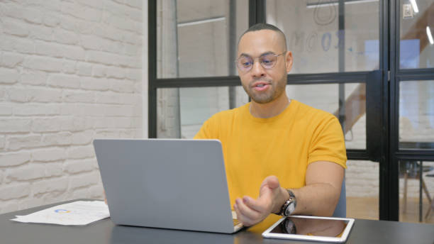 istock Hispanic Man Chatting Online on Laptop while Sitting in Office 2148475913