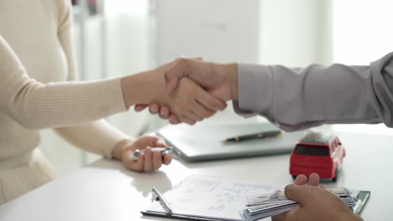 A car dealer sells cars or an Asian sales manager offers cars for sale and explains and reads the conditions for signing a car contract and insurance.
