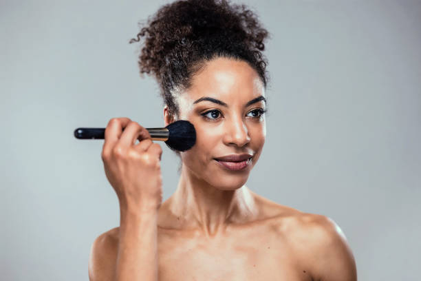 istock Beautiful young woman making make-up while looking at camera in isolated white 2148479393