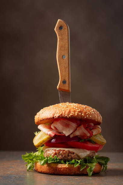 istock Fresh burger with knife on a brown background. 2148480410