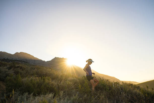 Female fell runner running downhill in mountains at sunset