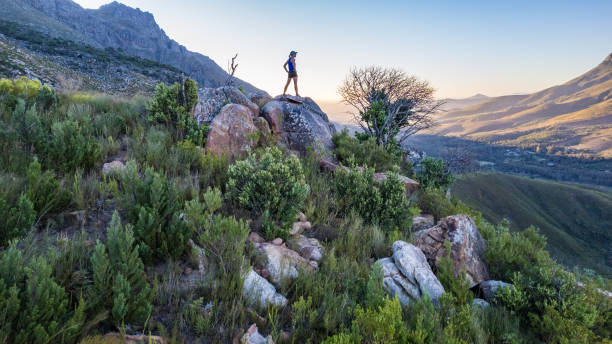 istock Female trail runner standing on mountain peak with a sunset view at mountain range 2148481436