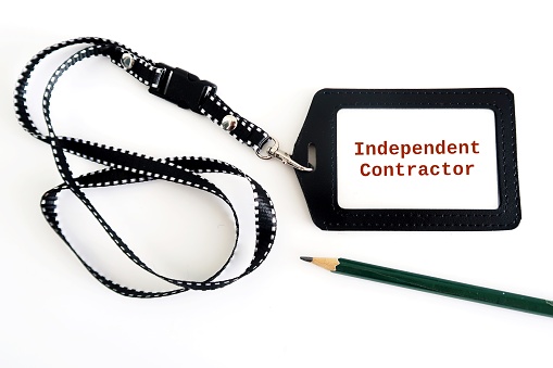 Pencil on white background with office card Independent Contractor - self-employed person or worker contracted to perform work or services as non-employee