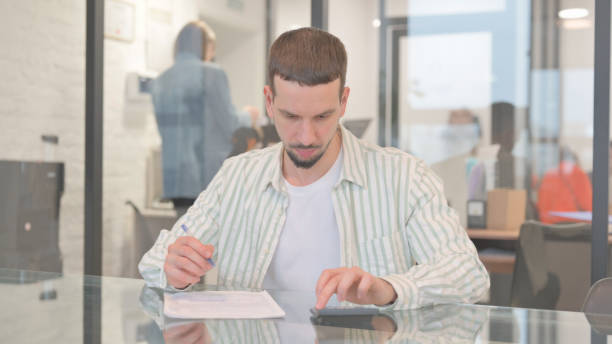 istock Creative Young Man Doing Financial Calculations of Business Report 2148484105
