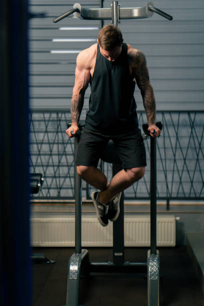 istock in the gym young handsome guy with tattoos pulls himself up and pumps his arms on the horizontal bar 2148485051