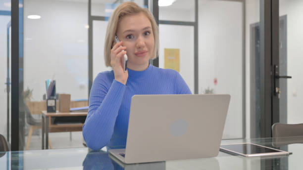 istock Young Woman Talking on Phone at Work 2148485336