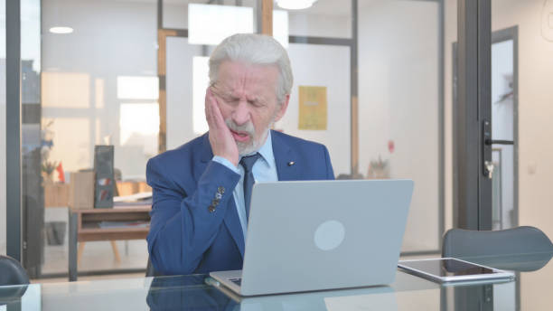 istock Senior Businessman with Toothache Working on Laptop in Office 2148485381