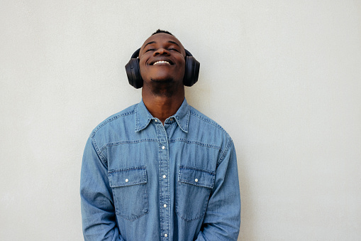 Cool dude american man in denim listening to favorite music playlist with headphones