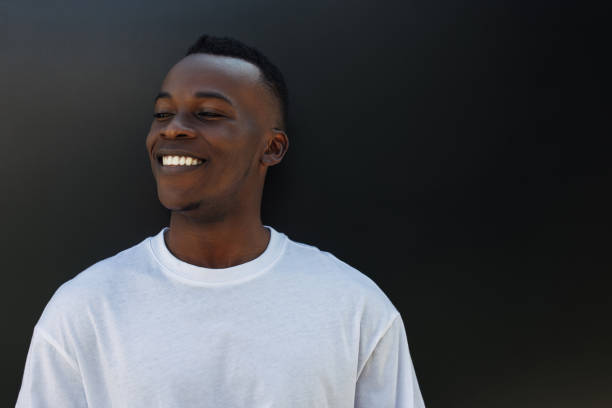 A cheerful and young guy smiles against a black background.