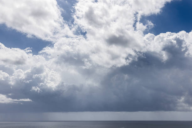 A dramatic view of the Ibiza seascape under a dynamic sky, where billowing clouds hint at an impending storm over the calm Mediterranean Sea