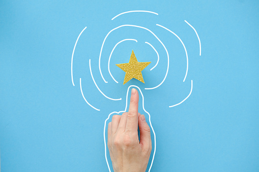 The finger of the hand points to a shiny star on a blue background. Best Customer Experience Concept in Business Services Rating