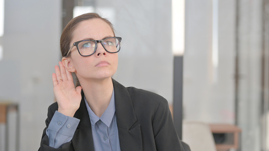 Portrait of Young Businesswoman Trying to Listen Secret information