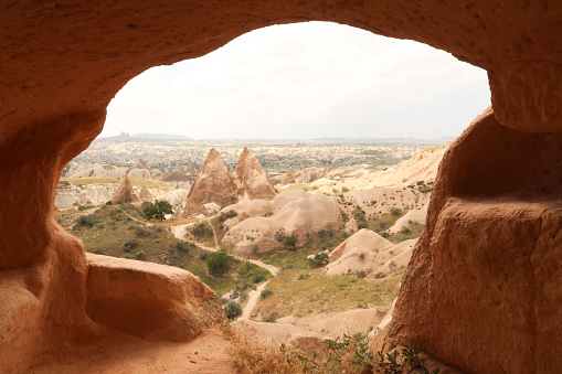 View out of a cave, window onto two fairy chimneys of the Red Valley, Rose Valley, Kizilcukur Vadisi next to the Cross, Crusader Church, Hacli Kilise, close to Göreme, Cavusin, Cappadocia, Turkey 2022
