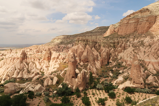 Panorama from a view point in the Red Valley, Kizilcukur Vadisi onto grape fields, vineyards, trees, fairy chimneys and red and pink rock formations, close to Göreme, Cavusin, Cappadocia, Turkey 2022