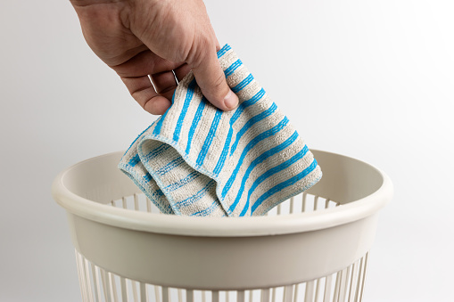 The kitchen towel is thrown into the trash can. Disposal of household waste.