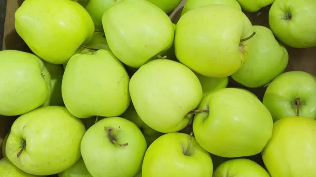 Lots of green apples during harvest in box or on store counter.