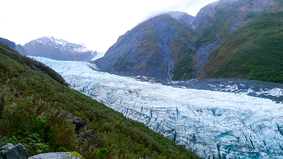 A glacier nestled among a mountainous valley on an overcast day