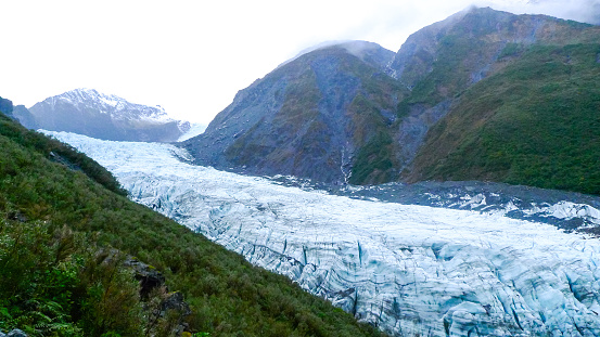 A glacier nestled among a mountainous valley on an overcast day