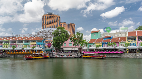 Tourist boats docking at Clarke Quay harbor timelapse hyperlapse with colorful houses. Clarke Quay is a historical riverside quay in Singapore, within the Singapore River Planning Area.