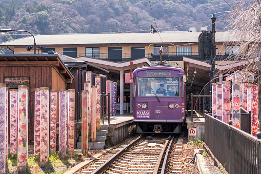 Kyoto, Japan - March 29 2024 : Train stop at Arashiyama station with the Kimono forest poles on both sides of the platform. Arashiyama Line operated by Keifuku Electric Railroad.