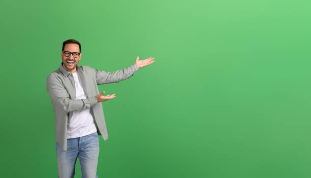 istock Young businessman laughing and presenting new product on empty space over isolated green background 2148497848