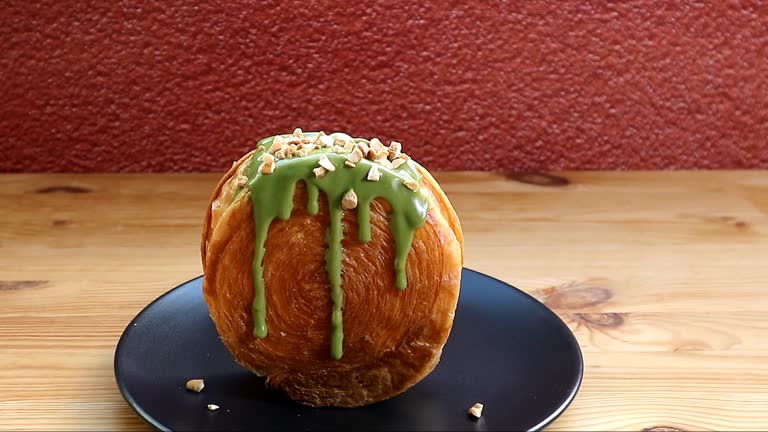 Footage of a Supreme Croissant Topped with Chopped Nuts and Matcha Green Tea Sauce