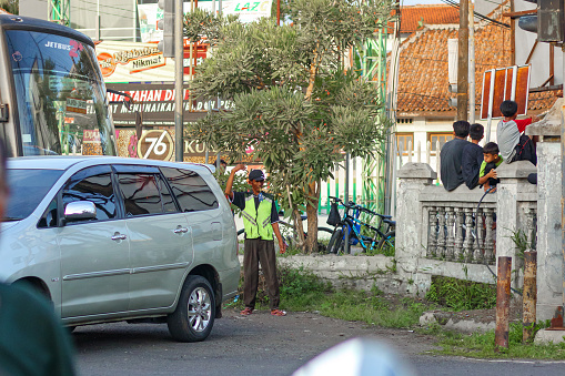 Cilacap, Indonesia - March 29, 2024 : A parking attendant who is helping a car driver to give directions in parking his car