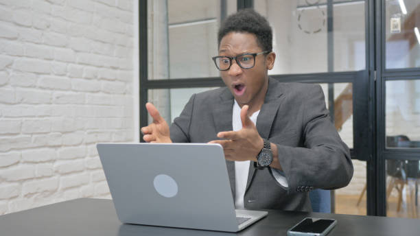 istock Young African Man Shocked by Loss on Laptop 2148501374