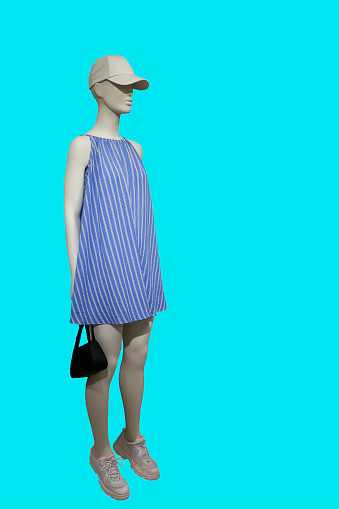 Full length image of a female display mannequin wearing fashionable blue striped dress sundress isolated on green background