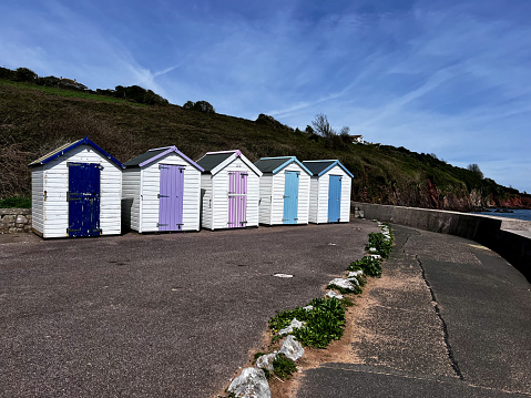 A row of five colourful beach huts on the promenade by the beach