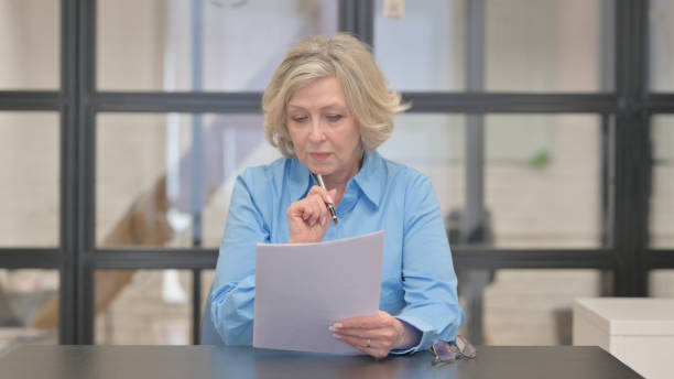 istock Old Businesswoman Reading Documents in Office 2148512218