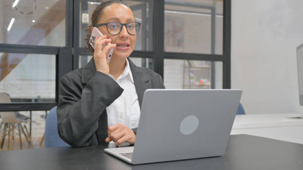istock Hispanic Business Woman Talking on phone at Work 2148514700