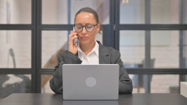 istock Angry Mixed Race Business Woman Talking on phone at Work 2148515044