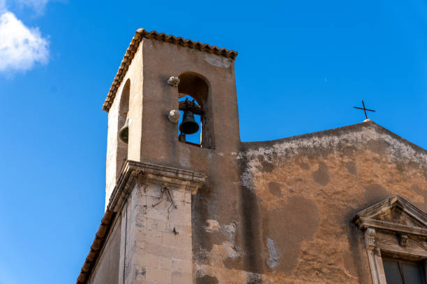 A bell tower with a bell hanging from it. The sky is blue and clear