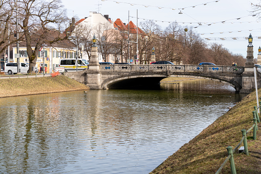 A bridge over a river with a city in the background. The water is calm and the bridge is old