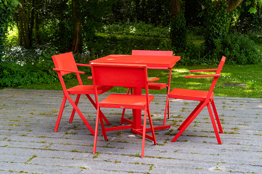Photo of colorful, red, yellow, blue, green, pink outdoor chairs and small table at a patio.