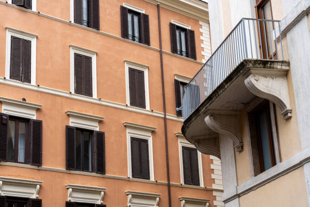 A brown building with a balcony and a window. The balcony is made of metal and has a railing