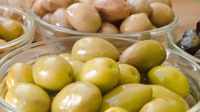 Marinated olives lie in a glass bowl