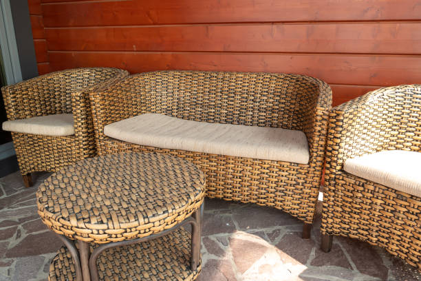 istock Wicker sofa set with round table on stone floor against wooden wall background 2148517257
