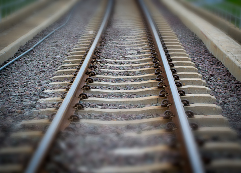 Closeup of railroad tracks, with a focus on one set shown in sharp detail and depth, set against an out-of-focus background of additional tracks.