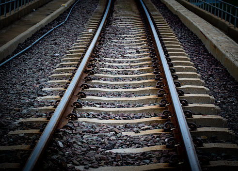 Closeup of railroad tracks, with a focus on one set shown in sharp detail and depth, set against an out-of-focus background of additional tracks.