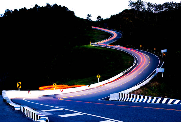 A winding road with a bright orange light in the distance