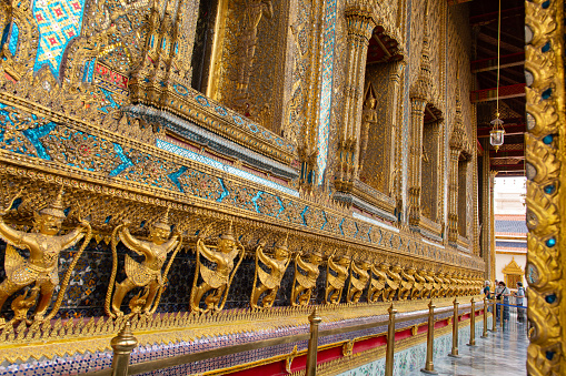The gold and blue wall is decorated with many statues of people. The wall is very ornate and has a lot of detail