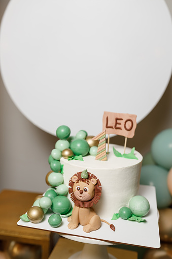 Children's birthday cake with lion figurine and balloons