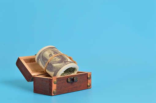 The concept of saving is symbolized by the image of money in a box, representing the discipline of setting funds aside for future goals and emergencies.