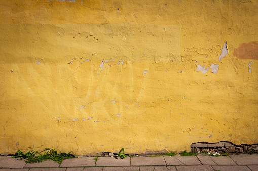 Old vibrant yellow street wall and pavement