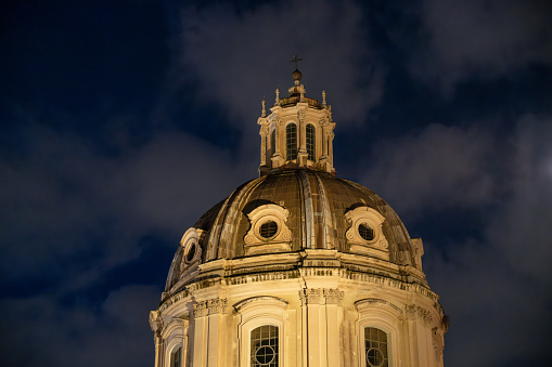 A large dome on top of a building with a cross on top. The building is lit up at night