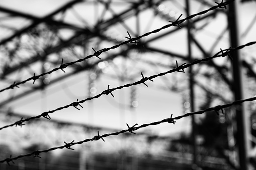 Barbed wire of a refugee camp with impossible escape in dramatic black and white